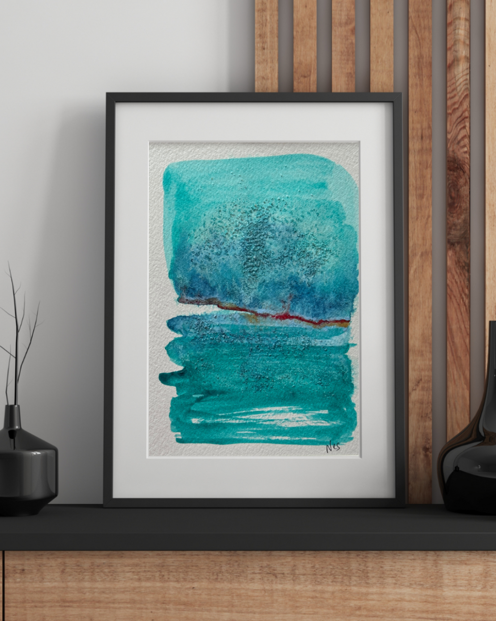 Framed abstract art piece with blue and green strokes on a wall.
